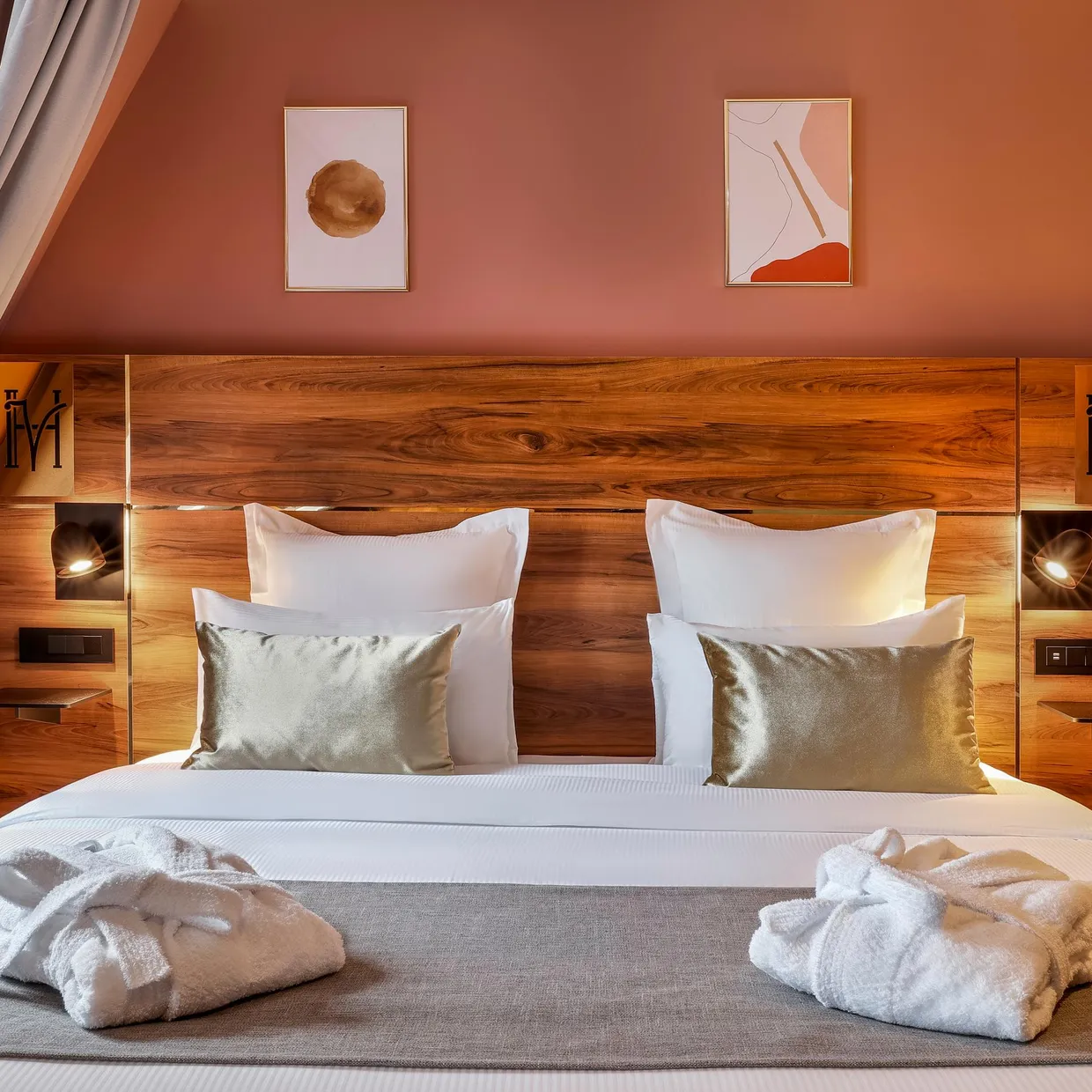Doppelbett mit Holz-Kopfteil, weißen Kissen und gefalteten Handtüchern auf der grauen Decke