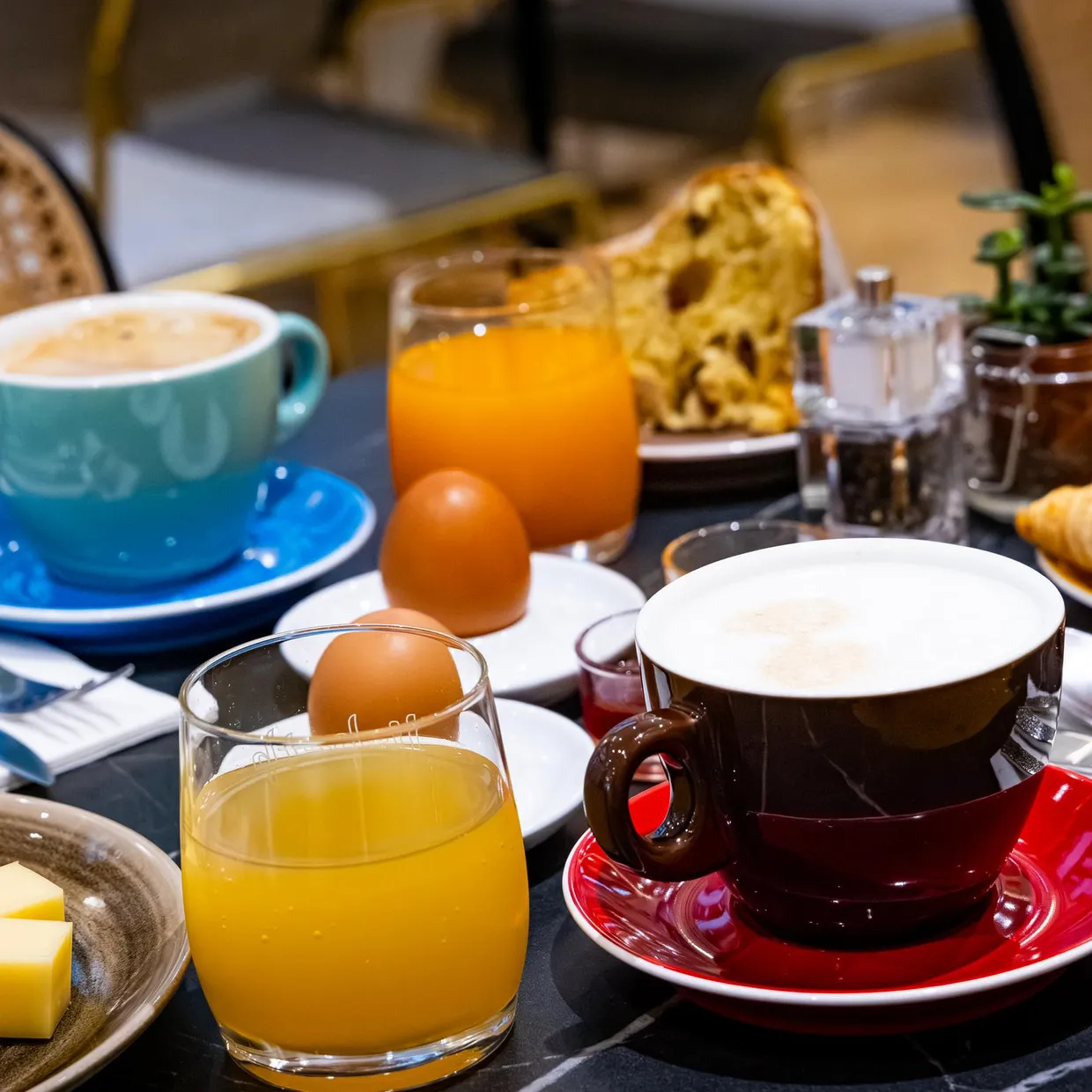 Frühstückstisch mit Kaffee, Orangensaft, Croissants, Eiern, Butter, Aufschnitt und Besteck