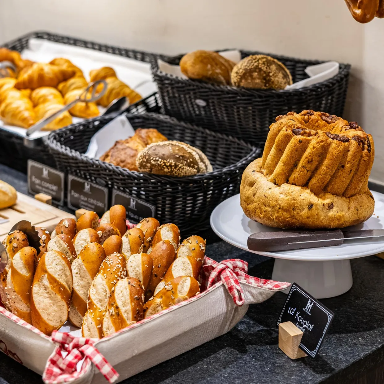 Sortiment an Brot und Backwaren, präsentiert auf Tabletts und in Weidenkörben mit Etiketten