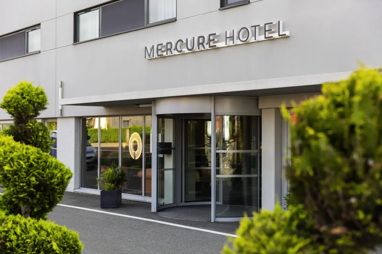 Haupteingang eines Mercure-Hotels mit grünen Pflanzen im Vordergrund