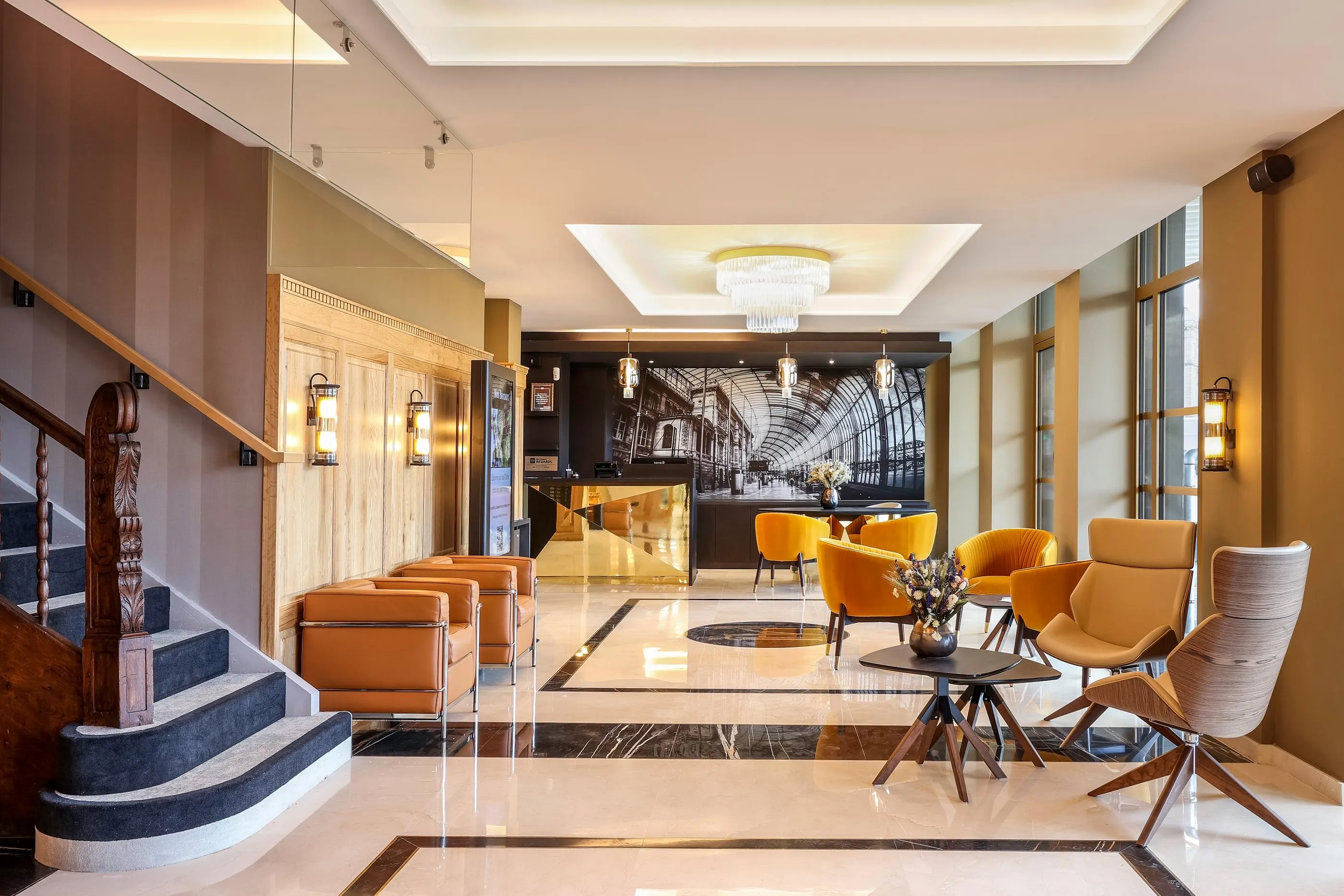 Hotellobby mit Sofas und Sesseln, einer Rezeption und einer Treppe an der Seite