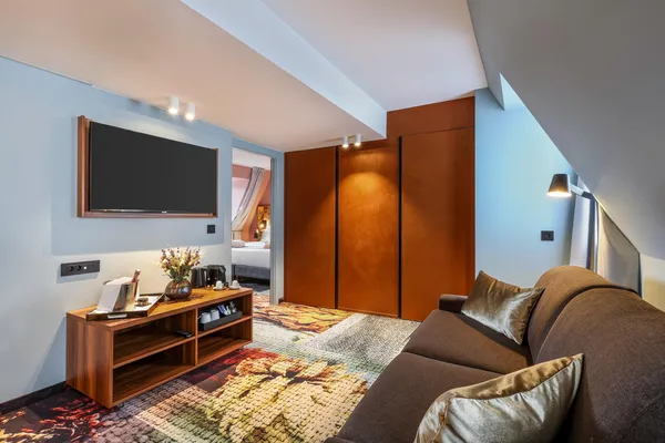 Hotel lounge with sofa, coffee table, television, and open door to the bedroom