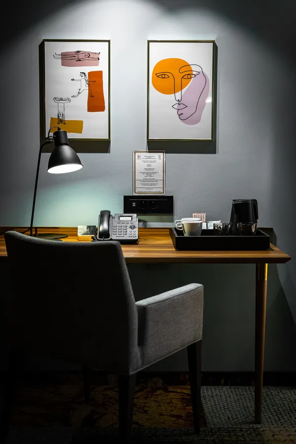 Office with telephone, floor lamp, two chairs, and two abstract paintings hung on the wall.
