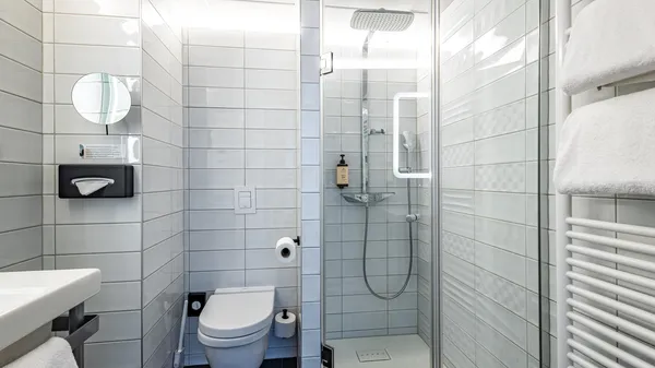 Bad mit Dusche, Toilette, Waschbecken, Handtüchern und Badezubehör