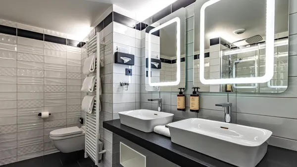 Modern bathroom with shower, sink, toilet, hanging towels, and toiletries on the counter