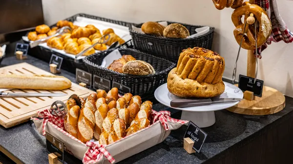 Sortiment an Brot und Backwaren, präsentiert auf Tabletts und in Weidenkörben mit Etiketten