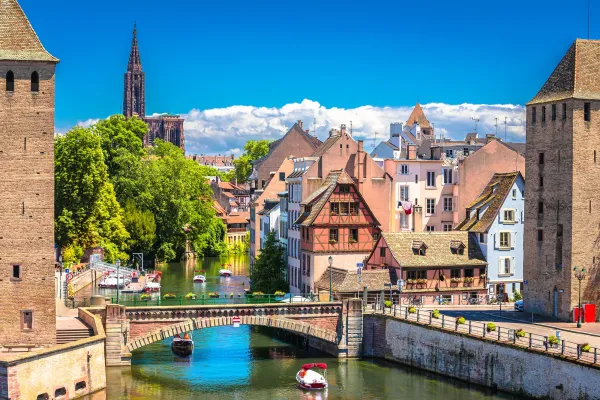 Blick auf einen Kanal mit traditionellen Häusern und einer gotischen Kathedrale im Hintergrund